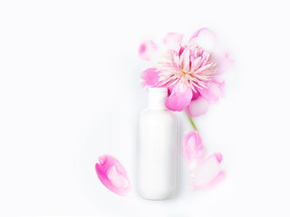 Obraz na płótnie Canvas Jars of cream and pink peony in a milk bath. Gentle care. Conceptual photo: the best cosmetic tool for body and face care. Copy space, flat lay. Natural cosmetics.