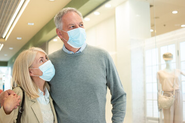 Elderly couple walking in a shopping mall during coronavirus pandemic