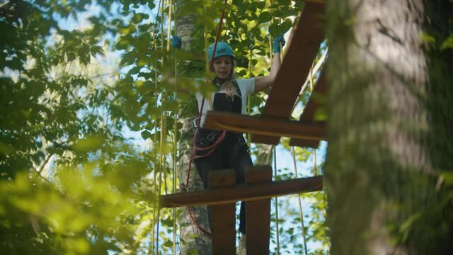 Woman in full insurance crossing the rope bridge - an entertainment attraction in the forest