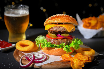 Big hamburger with salad, french fries, onion rings and cheese.