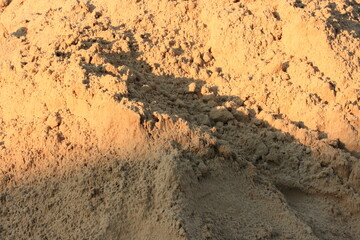Background of river sand after rain in the rays of sunset