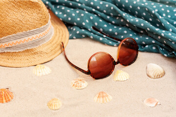 Vintage summer wicker straw beach hat, pareo and sunglasses on the seashore of Catania, Sicily, Italy.