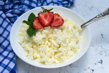 Plate of cottage cheese and strawberries on a blue background. 