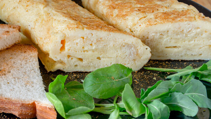 French omelet close-up on a black plate with lettuce and croutons