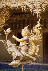 Golden colored statue in Thay style - Boy Riding a Fish Dragon at Famous Wat Rong Khun, White Temple in Chiangrai, Chiang Rai Province, North Thailand