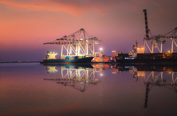 The transportation of cargo ships, containers and the beauty of the water reflection at the harbor when the sky after sunset In the industry engaged in the import and export business of maritime