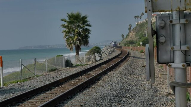 Railroad at California coast train moving between palms next to ocean pacific surfliner in San Clemente