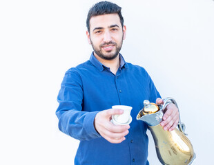 Arabic guy holding coffee pot in his hand and presenting cup