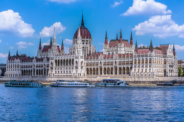 Fototapeta na wymiar A view of the east bank of the River Danube in Budapest towards the Parliament Building and river ferry boats during summertime