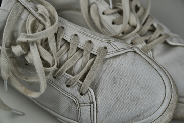 Dirty, used, muddy white dirty pair of shoes on white dirty floor