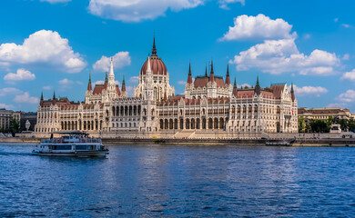 Obraz premium A view of the River Danube in Budapest towards the Parliament Building and river ferry during summertime