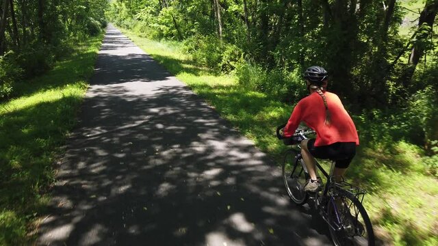 Aerial From Behind Of Cyclist Happy Woman On Bicycle. Shirt Blowing When Girl Cycling. Handsome Female Cycling On Bike. Beautiful Woman Hair Fluttering. Adorable Cyclist Girl Workout. Fun Sport.