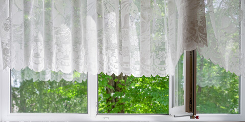 light breeze blowing white transparent fabric curtain through white open large window plastic frame