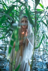 Mermaid girl bride in white dress in lake. Fantasy girl. Mysterious scene. Witch standing in the river and practice witchcraft. Fairytale