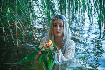 Mermaid girl bride in white dress in lake. Fantasy girl. Mysterious scene. Witch standing in the...