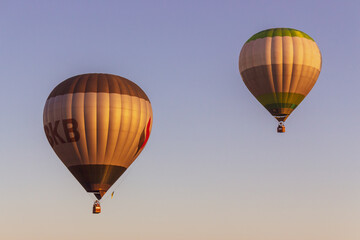 Kyiv, Ukraine - 06/27/2020: Hot air balloons in clear blue sky. Colorful balloons with basket lift up. Summer adventure and leisure. Aviation sport concept. Two balloons in morning light. 