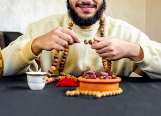 Arabic muslim man holding rosary with some date infront of him