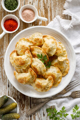 Baked dumplings stuffed with mushrooms and lentils on a white plate on a wooden table, top view