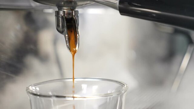 Making fresh coffee beverage going out from coffee espresso machine. Slow motion food video. Espresso coffee being brewed by automatic machine flowing into cup at bar or cafe. Full hd