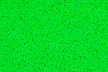 A macro photo of a green gradient color with texture from real foam sponge paper for background, backdrop or design.