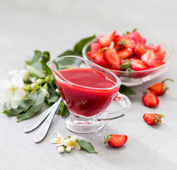Strawberry sauce in a glass saucepan on a light background