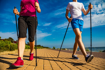 Nordic walking - middle-aged woman and young man training by the sea shore