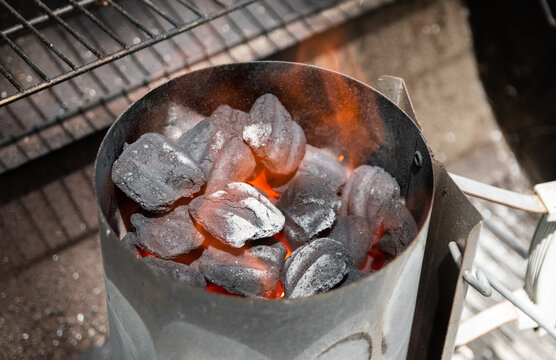 Coals burning in charcoal chimney starter on grill