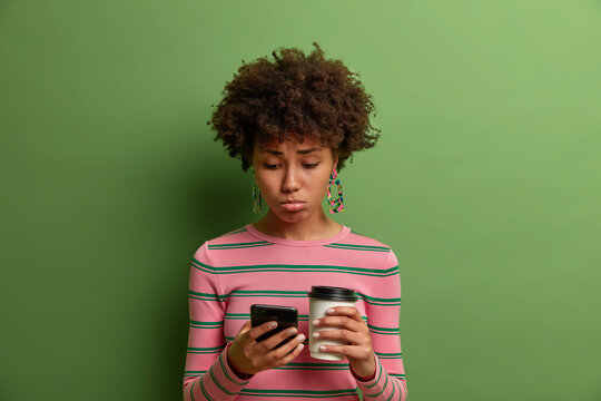 Sad Upset Woman Scrolls Social Networks, Canot Download Necessary Information, Uses Phone Application, Drinks Takeaway Coffee, Dissatisfied With Mobile Service, Isolated On Green Studio Background