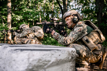Fototapeta premium Two soldiers in camouflage sit in ambush in the forest thicket