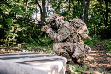 Army soldier sitting in ambush in the forest with a rifle