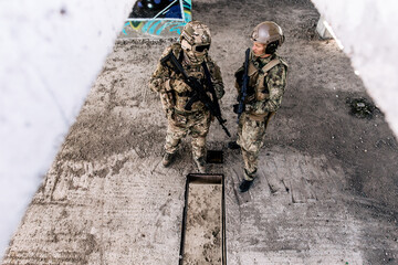 Two us army soldiers patrolling the streets standing in a building talking to each other view from above