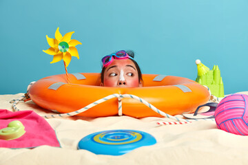 People, summer, relaxation, holiday concept. Curious woman buried in sand, looks from inflated...