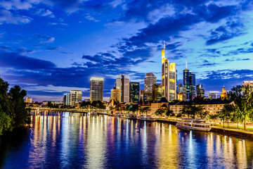 Obraz premium Frankfurt am Main. European finance center city downtown skyline cityscape. Eiserner steg bridge, river during twilight blue hour, sunset, evening, night. Gold yellow color. Travel in Hesse, Germany.