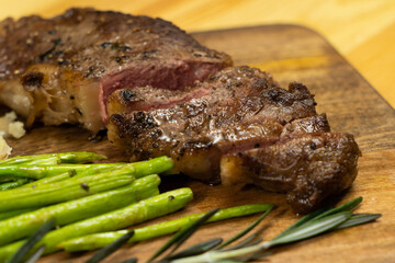 Raw beef steaks ready for preparation with rosemary, garlic, and spices in cast iron grill frying on black. Top view