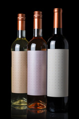 Bottles of red, white and rose wine isolated on black background.