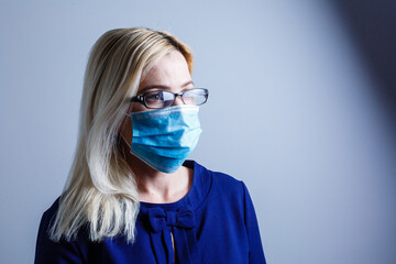 an attractive young woman wears a paper face mask to protect herself from the H1N1 Virus, isolated on white, with room for your text