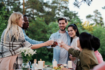 Young joyful friends of various ethnicities cheering up with glasses of wine