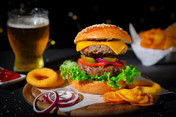 Big hamburger with salad, french fries, onion rings and cheese.