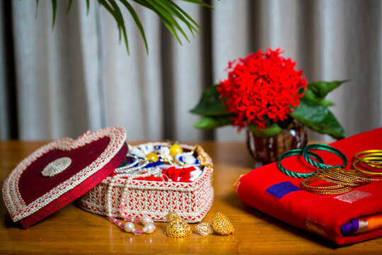 Handmade fiber ornaments box with traditional jewelry on the wooden table. Indian traditional jewelry and Bridal saree.