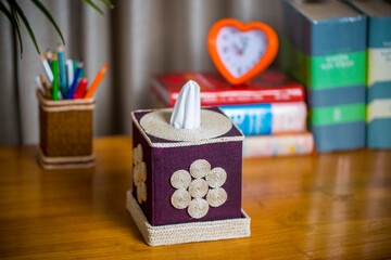 A tissue box on a wooden reading table. A tissue box made of fiber. Pineapple leaf fiber.
