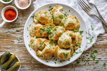 Baked dumplings stuffed with mushrooms and lentils sprinkled with chopped fresh parsley on a white plate on a wooden table, top view