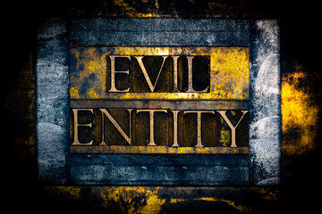 Evil Entity text formed with real authentic typeset letters on vintage textured silver grunge copper and gold background