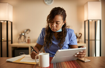 filipina nurse working from home doing paperwork and using tablet
