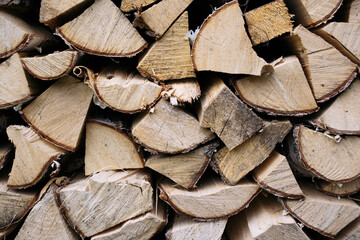 Fototapeta premium Closeup photo of many firewood evenly stacked against the wall. Dry wood logs. Beautiful texture.