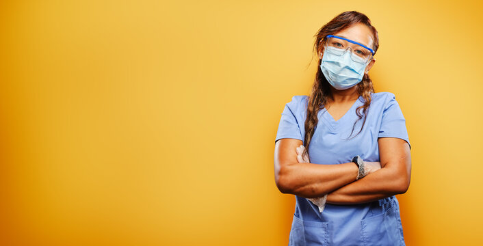 filipina nurse wearing facemask and PPE on orange background