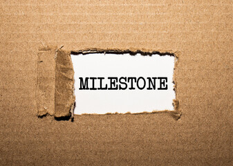 The text MILESTONE. behind torn brown paper