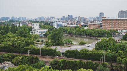 Fototapeta na wymiar Railway between trees and city skyline viewed from South Lake scenic area in Jiaxing, China