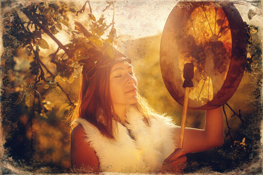 beautiful shamanic girl playing on shaman frame drum in the nature. Old photo effect.