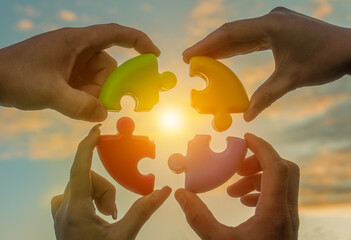 Four hands of businessmen connect colored pieces of the puzzle into a single whole. Business...