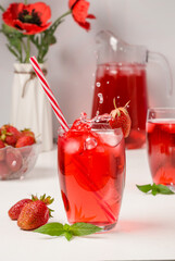 Summer strawberry drink with a splash of falling ice on a white wooden background.